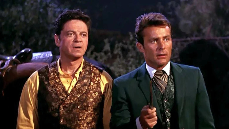 Artemus Gordon (Ross Martin) stands next to Jim West (Robert Conrad) as he holds a knife in The Wild Wild West