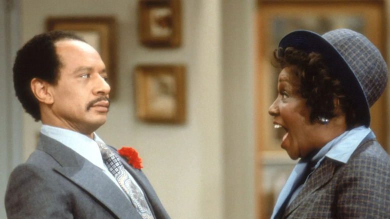 George Jefferson (Sherman Hemsley) leans away from a jubilant Louise Jefferson (Isabel Sanford) in The Jeffersons