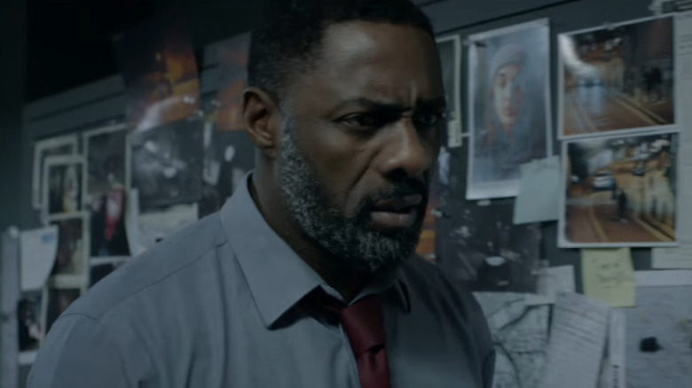Idris Elba as John Luther, standing in front of a board of pictures on Luther