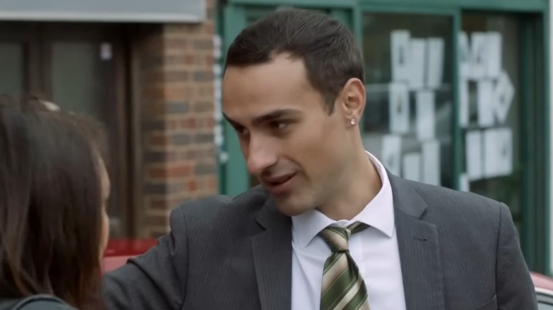 Jamie Demetriou as Stath Charalambos, leaning on a car in Stath Lets Flats