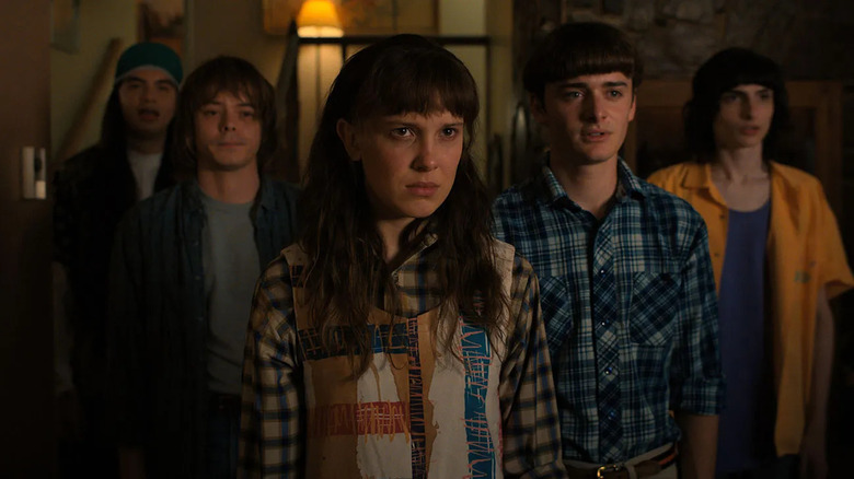 Argyle (Eduardo Franco), Jonathan Byers (Charlie Heaton), Eleven (Millie Bobby Brown), Will Byers (Noah Schnapp), and Mike Wheeler (Finn Wolfhard) stand in a row on Stranger Things