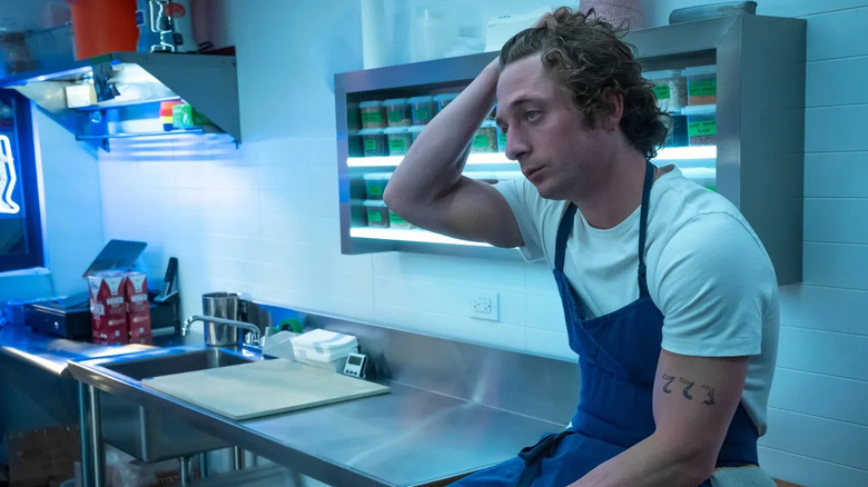 Carmy Berzatto (Jeremy Allen White) sits on a kitchen counter while running his hand through his hair on The Bear