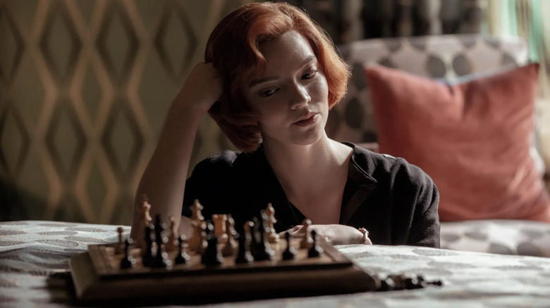 Beth Harmon (Anya Taylor-Joy) glances at a chess set on a bed on The Queen's Gambit
