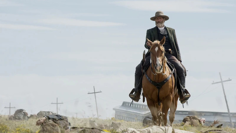 Frank Griffin (Jeff Daniels) rides a horse over strewn bodies in Godless