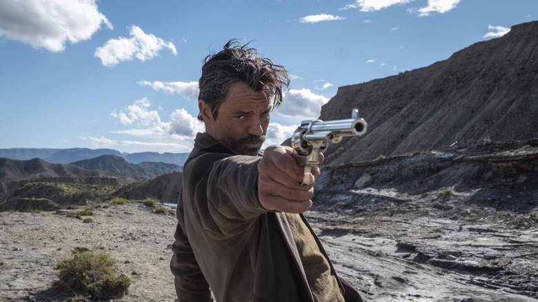 Arthur McCoy (Dominic Cooper) draws a pistol in a canyon in That Dirty Black Bag