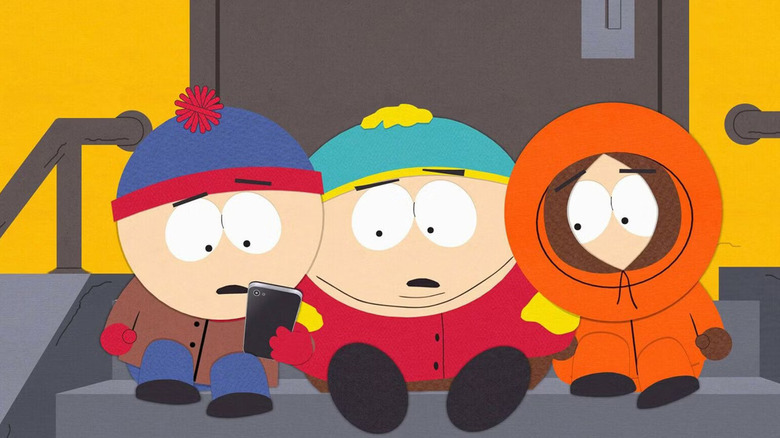Stan (Trey Parker), Cartman (Trey Parker), and Kenny (Matt Stone) stare at a phone in South Park