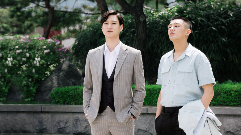 Shin Yool and Seo Hwi-young standing by each other in a park in Chicago Typewriter
