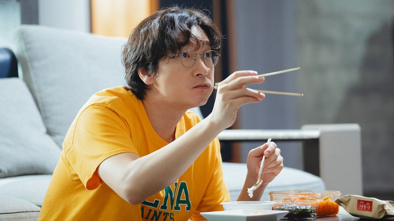 Shin Sung-han pointing with chopsticks while eating at a coffee table in Divorce Attorney Shin