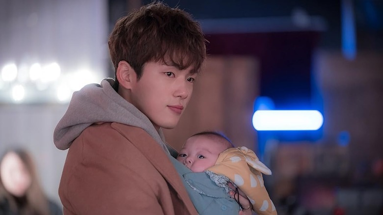 Kang Dong-gu holds an infant tenderly in Welcome to Waikiki