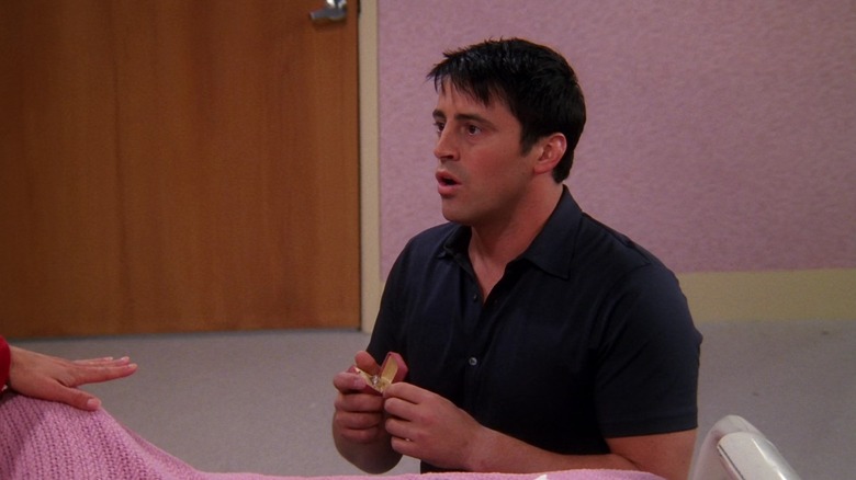 Matt LeBlanc as Joey, on his knees, holding a ring box with a shocked look on his face on Friends