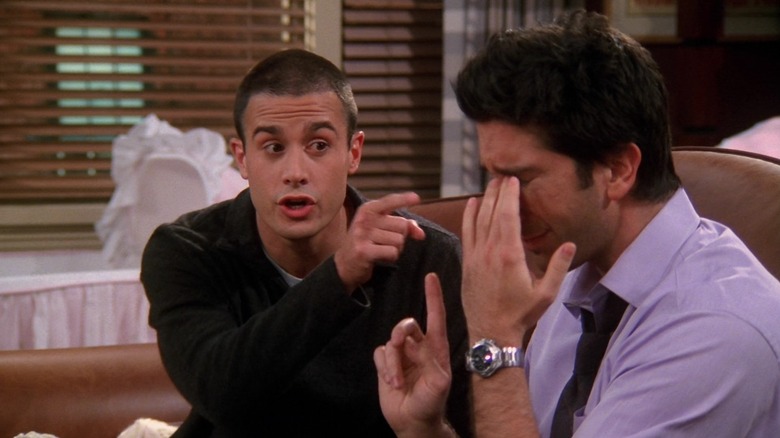 Freddie Prinze Jr. as Sandy and Ross, sitting on the couch while Ross (David Schwimmer) cries on Friends