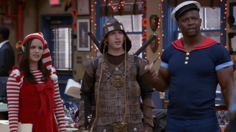 Jake Peralta (Andy Samberg), Amy Santiago (Melissa Fumero), Terry Jeffords (Terry Crews) standing in Halloween costumes in Brooklyn Nine-Nine