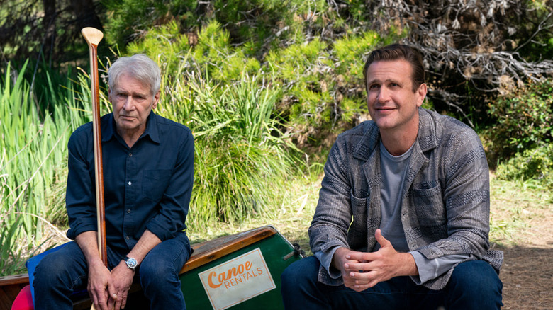 Paul Rhoades (Harrison Ford) grimaces while sitting and holding a paddle next to a smiling Jimmy Laird (Jason Segel) on Shrinking