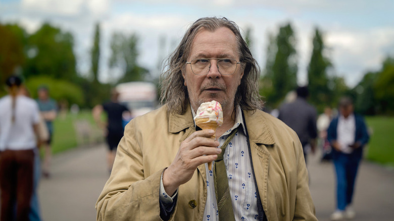 Jackson Lamb (Gary Oldman) eats an ice cream cone while walking through a park on Slow Horses