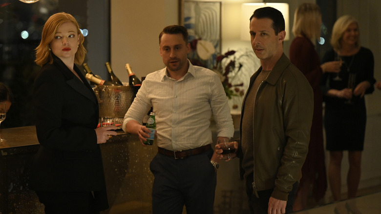 Shiv (Sarah Snook), Roman (Kieran Culkin), and Kendall (Jeremy Strong) at a party looking at someone