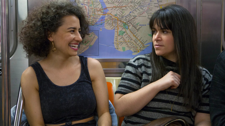 Ilana Glazer and Abbi Jacobson as Ilana Wexler and Abbi Abrams, laughing together on the subway in Broad City