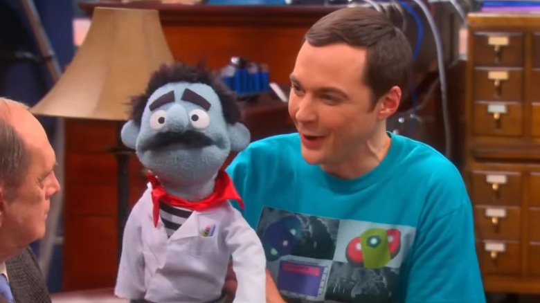 Sheldon showing Professor Proton his Gino the Neutrino puppet