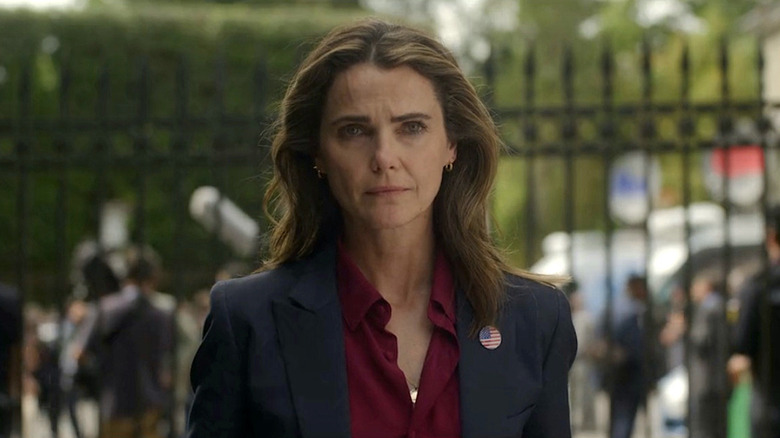 Keri Russell as Kate Wyler looking sad in front of wrought-iron fence in The Diplomat