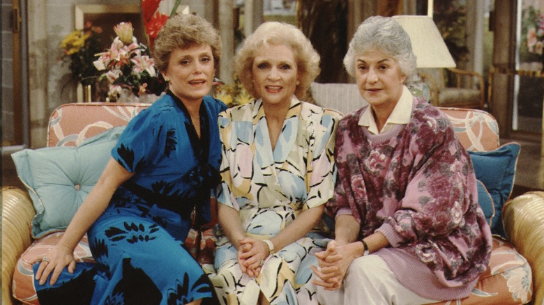 Blanche Devereaux, Rose Nylund, and Dorothy Zbornak smiling on couch on The Golden Girls