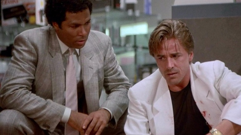 Philip Michael Thomas como Detetive Tubbs e Don Johnson como Detetive Crockett parecendo curvado e preocupado em Miami Vice