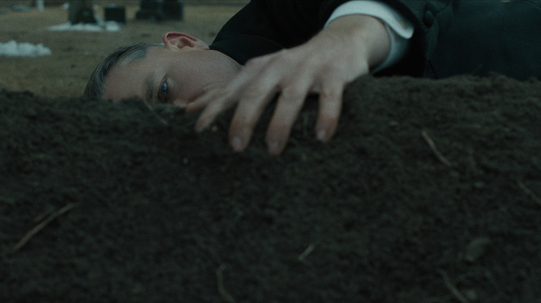 Ed Gein lying beside a grave on Monster: The Ed Gein Story