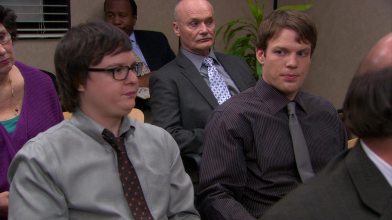 Clark Duke and Jake Lacy as Clark Green and Pete Miller, sitting next to each other in the conference room on The Office.