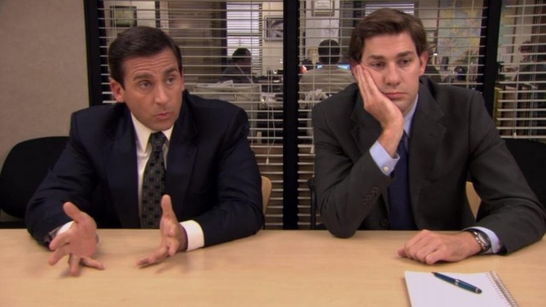 Steve Carell and John Krasinski as Michael Scott and Jim Halpert, sitting together in the conference room on The Office.