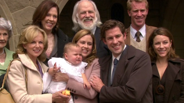 Jenna Fischer as Pam Beesly holds baby Cecelia with John Krasinski as Jim Halpert and others guests on The Office