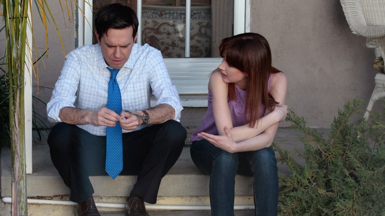 Ed Helms as Andy Bernard sits next to Ellie Kemper as Erin on The Office