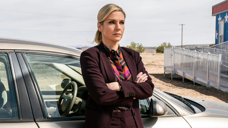 Kim Wexler leans against her car with her arms crossed in a maroon suit in "Better Call Saul"