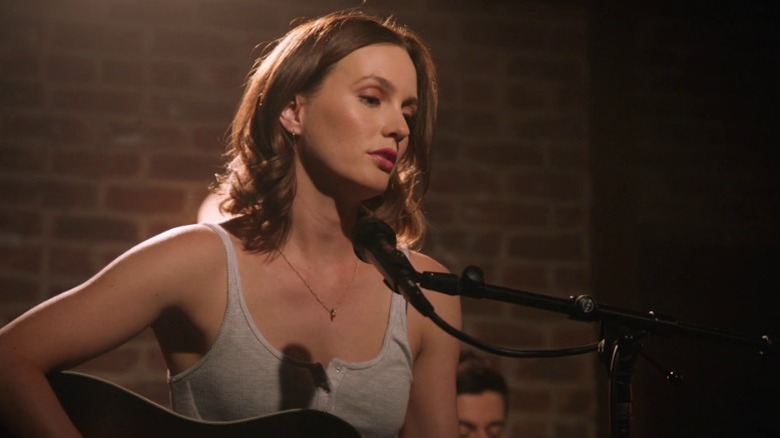 Laura singing and playing guitar on a stage on The Orville S2E11