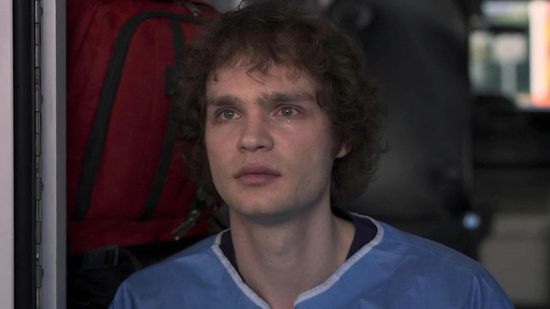 James Ogilvie in a blue hospital uniform with tears in his eyes