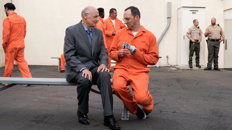George Bluth Sr. sits on a prison bench wearing a suit next to his son Buster wearing an orange prison jumpsuit on Arrested Development (2003-2019)