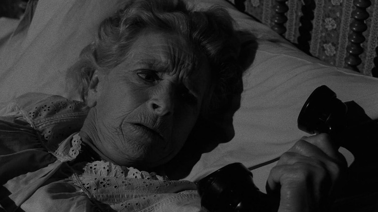 Elva Keene (Gladys Cooper) glances at a phone while laying in bed in The Twilight Zone