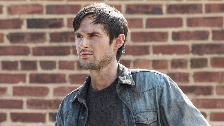 Andrew J. West as Gareth, standing near a wall in The Walking Dead.