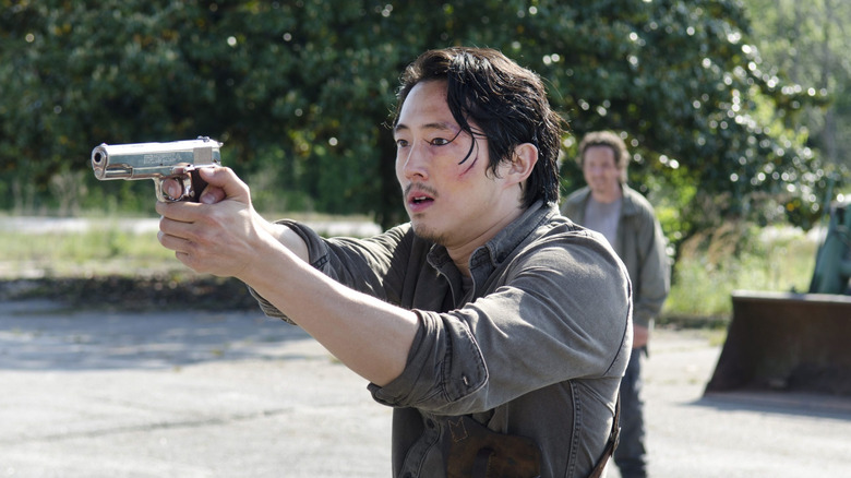 Steven Yeun as Glenn Rhee, aiming a gun in The Walking Dead.