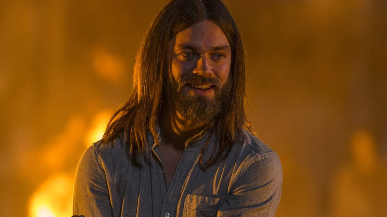 Tom Payne as Jesus, smiling near fire in The Walking Dead.