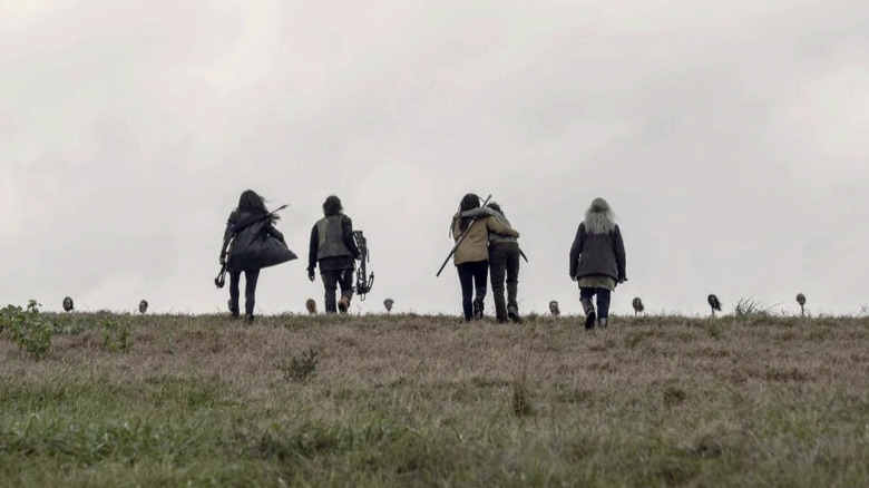 Community members walk toward the pikes in The Walking Dead.