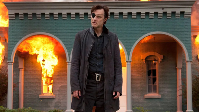 David Morrissey as The Governor, walking from a burning house in The Walking Dead.