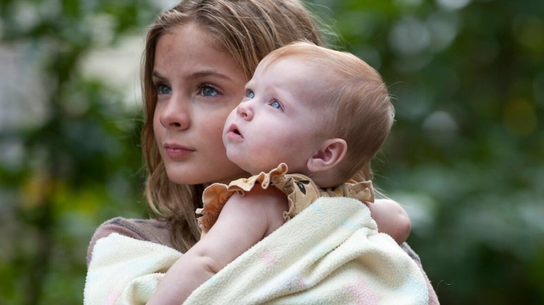 Brighton Sharbino as Lizzy Samuels holds a baby in The Walking Dead