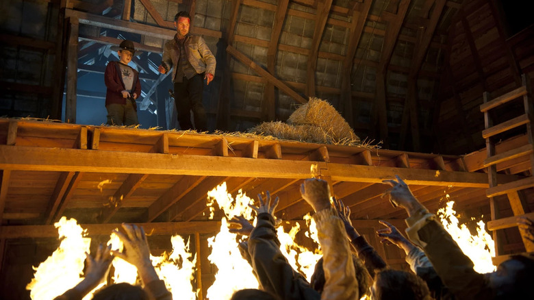 Carl Grimes (Chandler Riggs) and Rick Grimes (Andrew Lincoln) stare at zombies in a burning barn on The Walking Dead