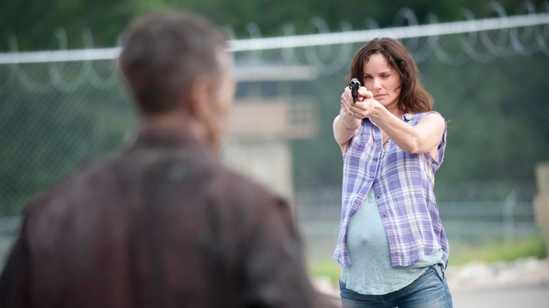 A pregnant Lori Grimes (Sarah Wayne Callies) aims a pistol at a zombie on The Walking Dead