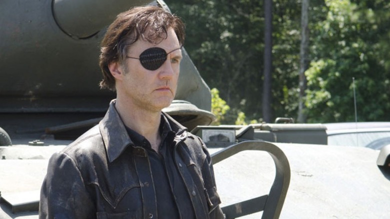The Governor (David Morrissey) stands grimly in front of a tank on The Walking Dead
