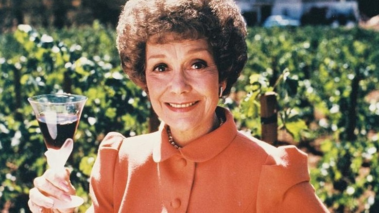Jane Wyman as Angela Channing holding up a glass of wine