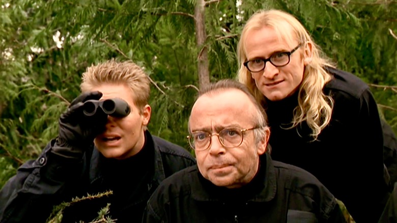 John Fitzgerald Byers dürbünle bakarken Melvin Frohike ve Ringo Langly izliyor