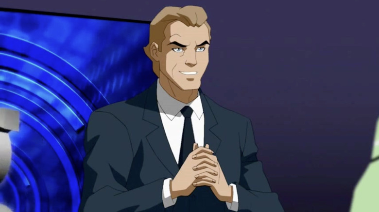 G. Gordon Godfrey with swept-back brown hair, a dark blue suit and tie, and a white shirt, with a blue display screen behind him.