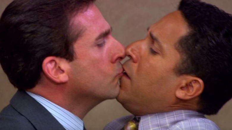 Steve Carell as Michael Scott lightly kissing a horrified Oscar Nuñez as Oscar on the lips in close-up on The Office