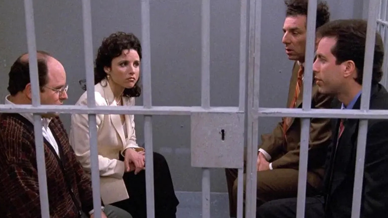 Jerry Seinfeld as Jerry Seinfeld sits in prison with Jason Alexander as George Costanza, Julia Louise-Dreyfuss as Elaine Benes, and Michael Richards as Cosmo Kramer in Seinfeld