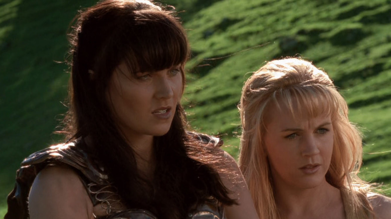 Lucy Lawless as Xena and Renee O'Connor as Gabrielle hear a stranger out in Xena: Warrior Princess.