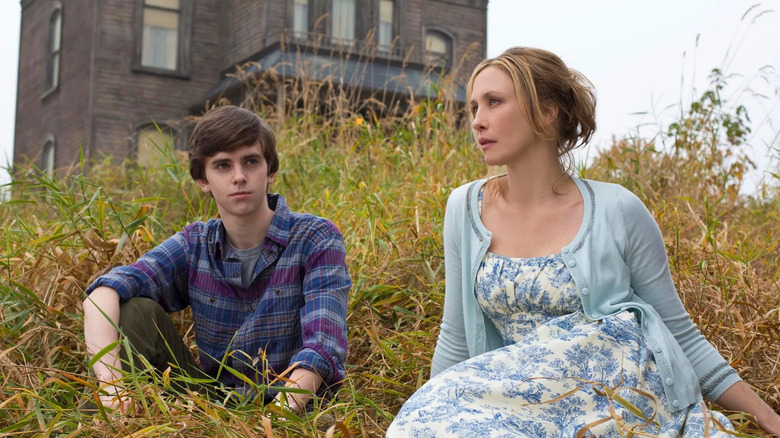 Freddie Highmore as Norman Bates and Vera Farmiga as Norma Bates, sitting in a field together in Bates Motel.